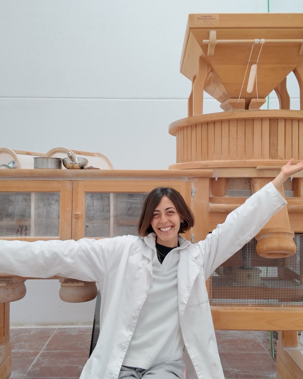 Almudena riendo junto al molino de piedra, en pleno taller